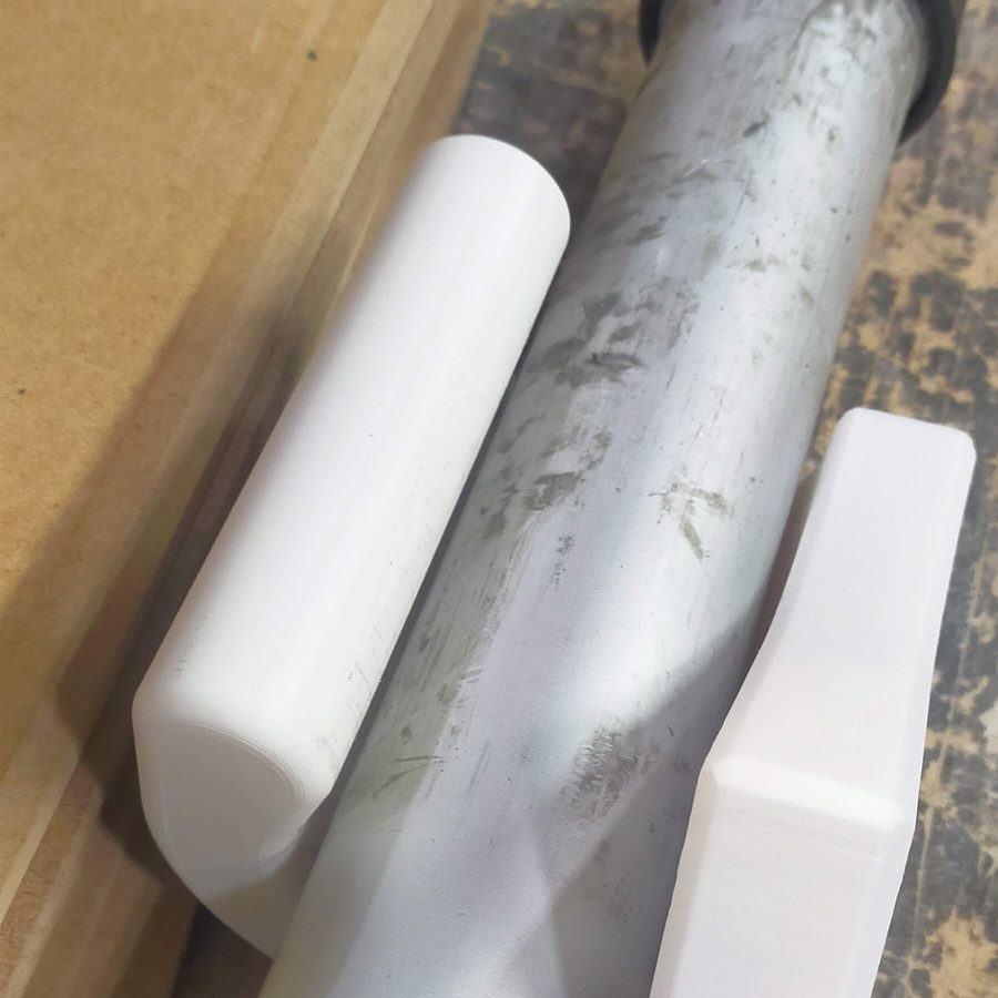 Two white 3D printed holder pieces cradling the barrel of the pneumatic gun
